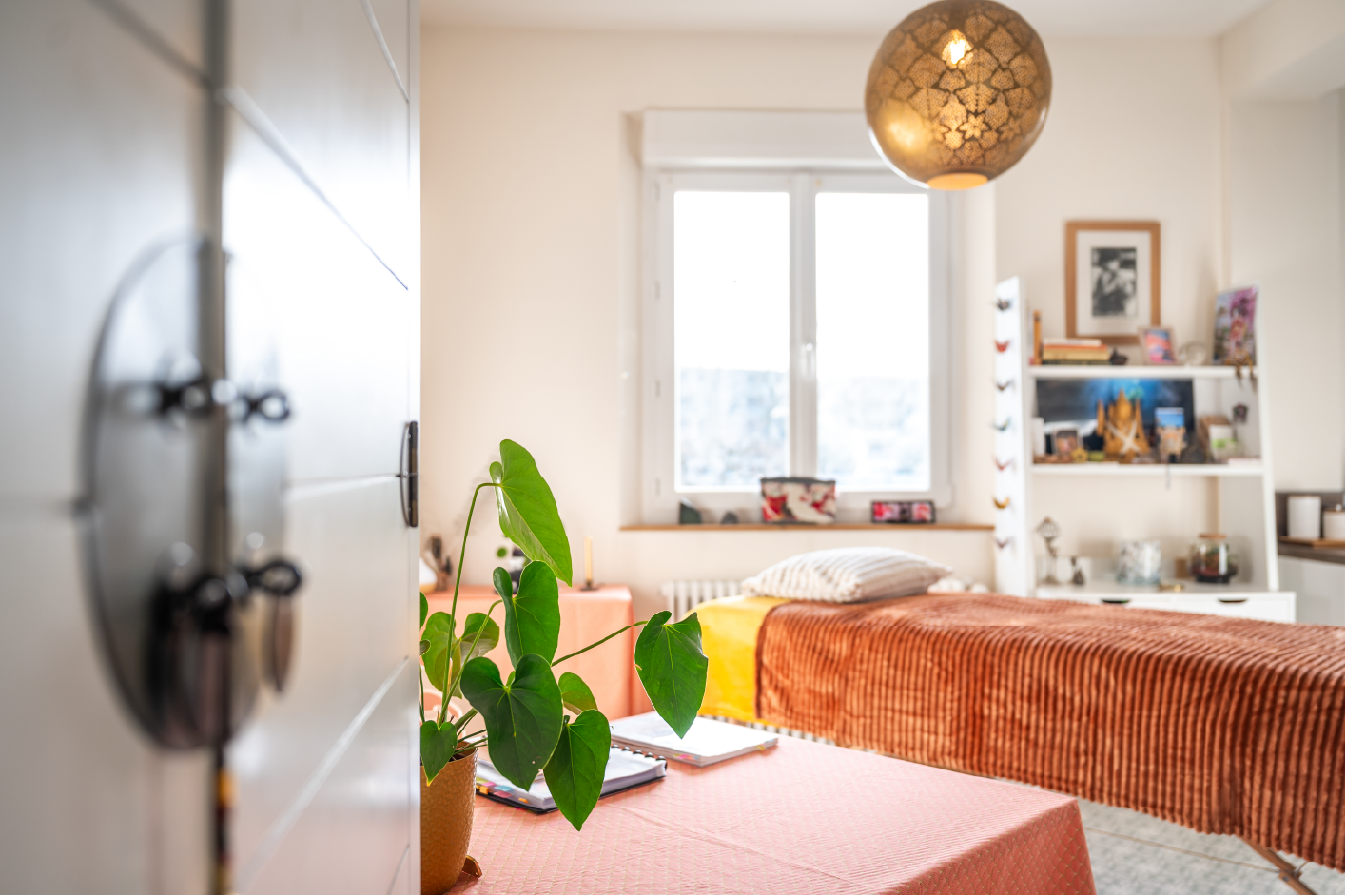 Entrée du cabinet de kinésiologie avec table de soin et plante verte